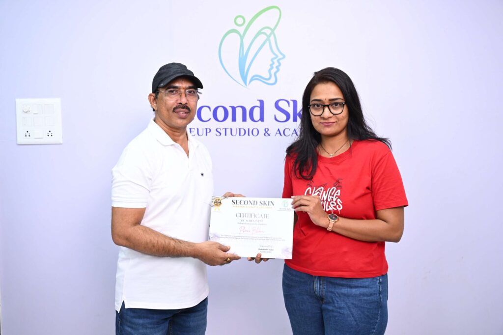 Student receiving a makeup course completion certificate from Chakravarthi Kadali at Second Skin Makeup Academy, Hyderabad