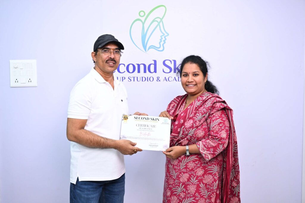 Student receiving a makeup course completion certificate from Chakravarthi Kadali at Second Skin Makeup Academy, Hyderabad