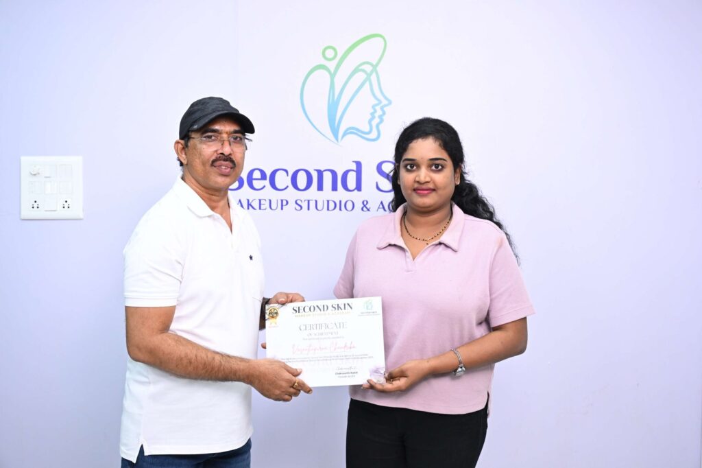 Student receiving a makeup course completion certificate from Chakravarthi Kadali at Second Skin Makeup Academy, Hyderabad