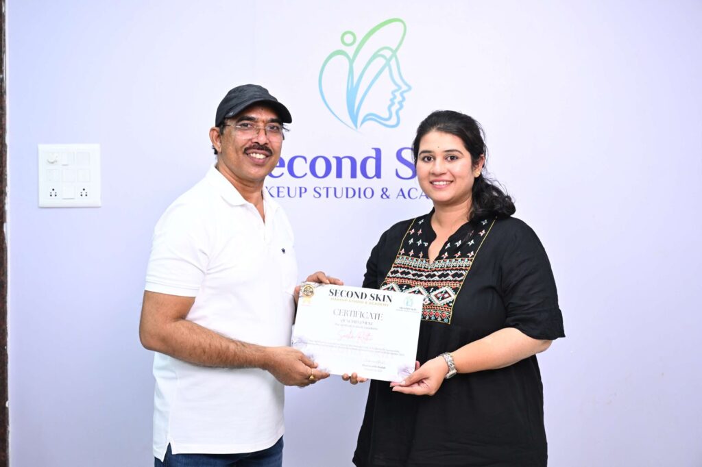 Student receiving a makeup course completion certificate from Chakravarthi Kadali at Second Skin Makeup Academy, Hyderabad