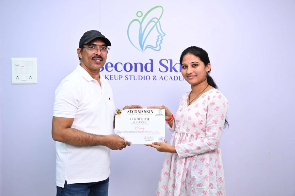 Student receiving a makeup course completion certificate from Chakravarthi Kadali at Second Skin Makeup Academy, Hyderabad