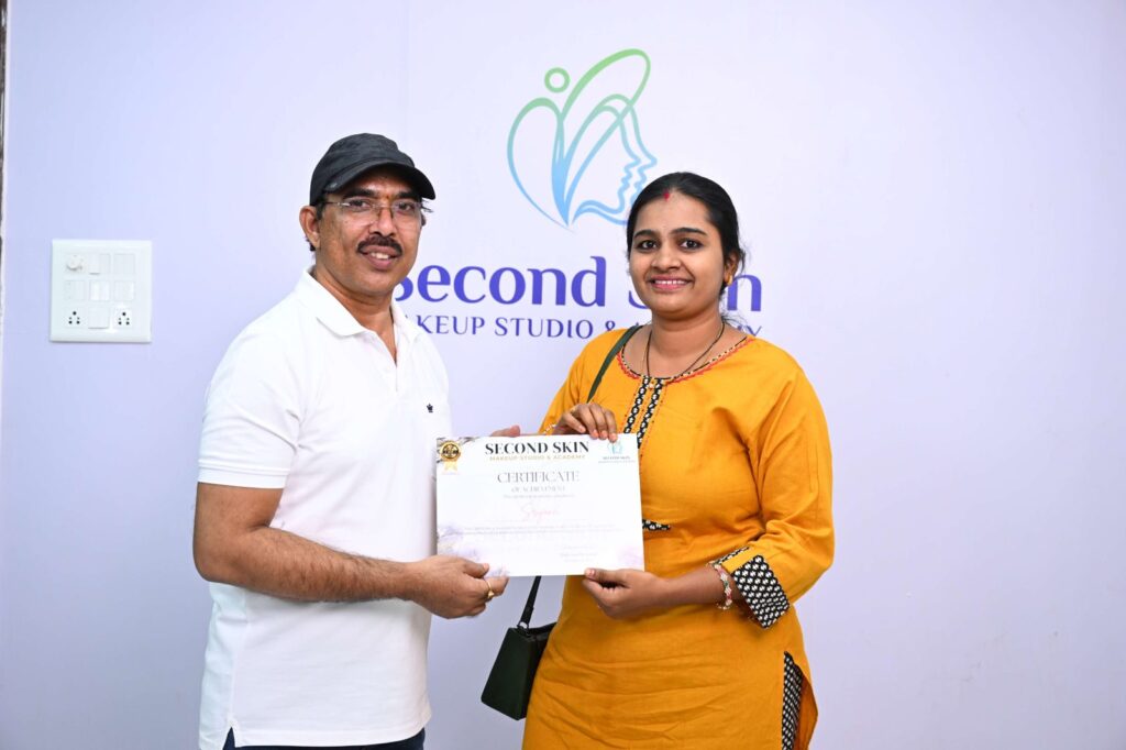Student receiving a makeup course completion certificate from Chakravarthi Kadali at Second Skin Makeup Academy, Hyderabad