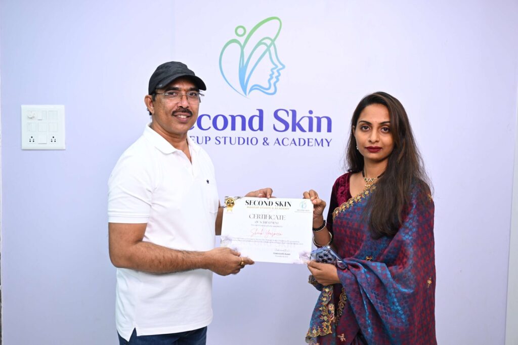 Student receiving a makeup course completion certificate from Chakravarthi Kadali at Second Skin Makeup Academy, Hyderabad