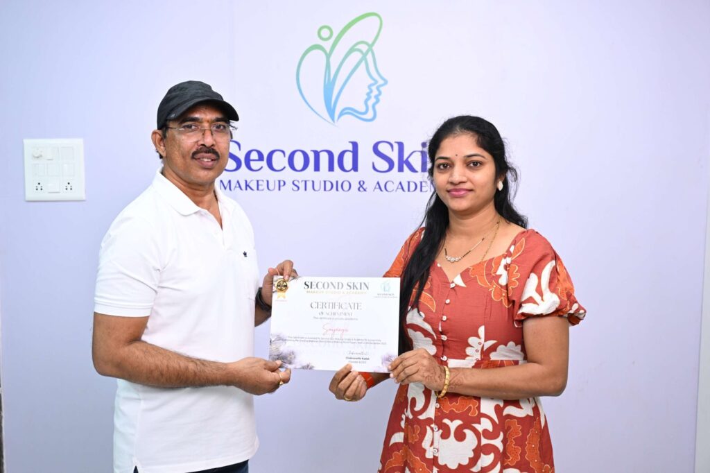 Student receiving a makeup course completion certificate from Chakravarthi Kadali at Second Skin Makeup Academy, Hyderabad