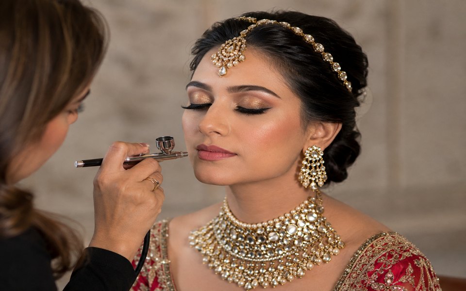 Makeup artist applying airbrush bridal makeup to a bride with an airbrush gun