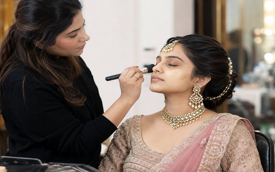 Makeup artist blending bridal base makeup on a bride with a brush during training in Hyderabad