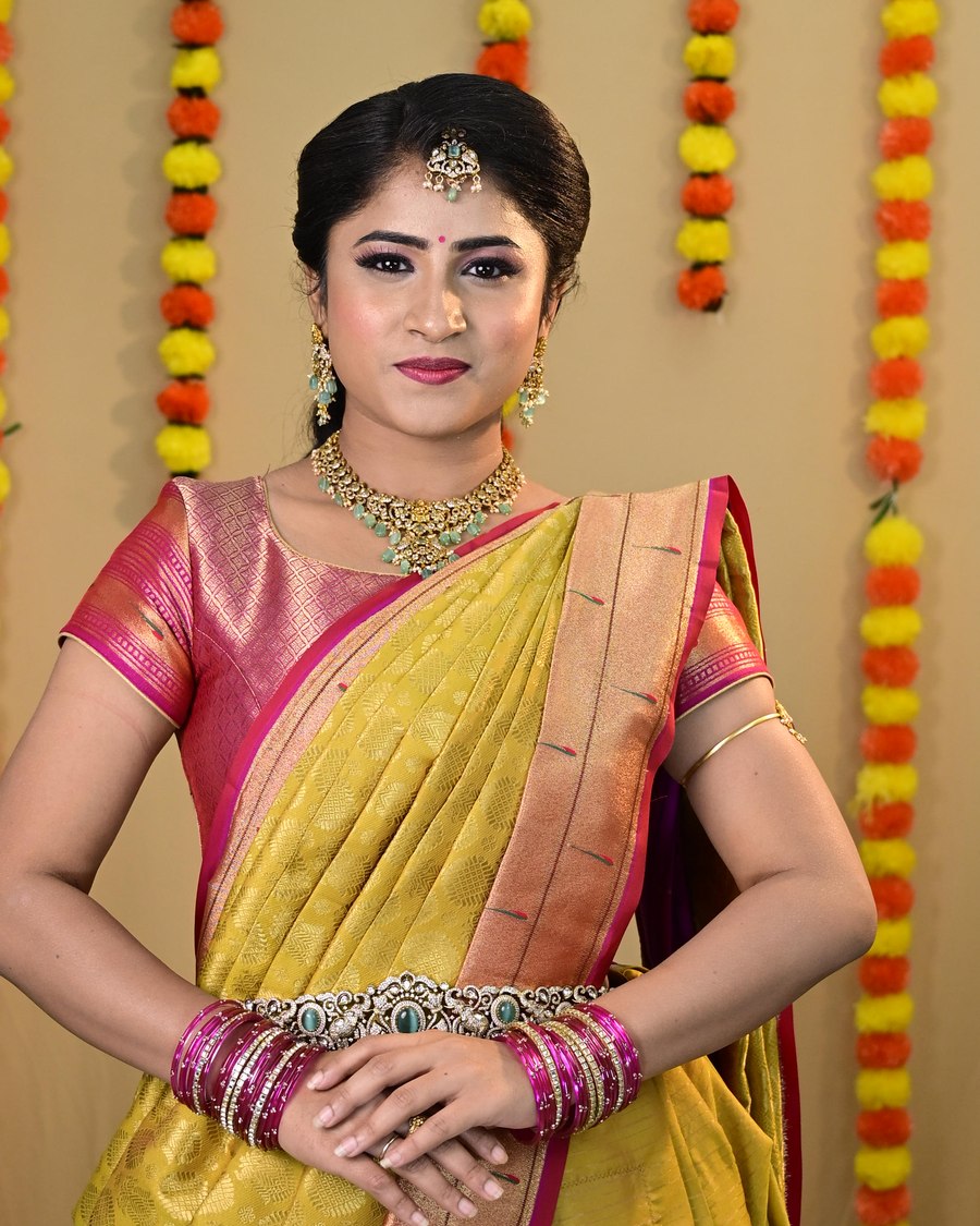 Woman wearing a yellow and pink Kanjivaram saree draped in a traditional South Indian style with temple jewellery