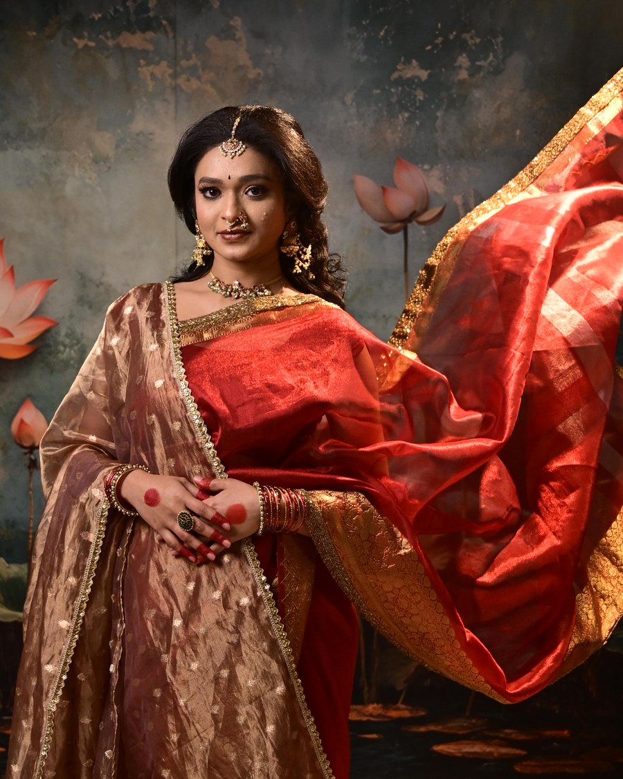 Woman in a red and gold silk saree with a pleated pallu draped over the shoulder