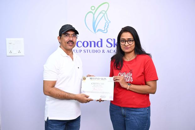 A student receiving her makeup course completion certificate from Chakravarthi Kadali at the Second Skin studio